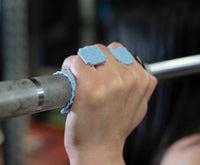 Hand gripping a barbell with blue sillygrip lifting pad in gym setting