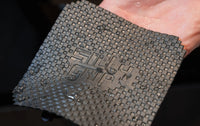 Wet textured grey lifting pad mat held by a hand with water droplets on it.
