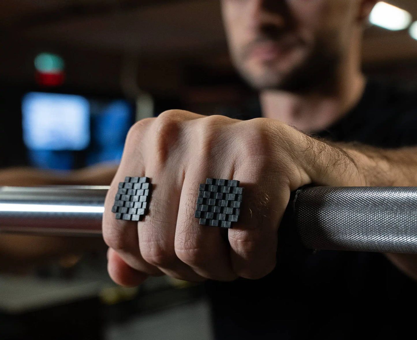 Close-up of a person's hands gripping a bar with visible top part of grey sillygrip weight lifting grip pad