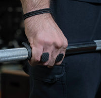 Hand holding a barbell with textured grips, wearing a black wristband 