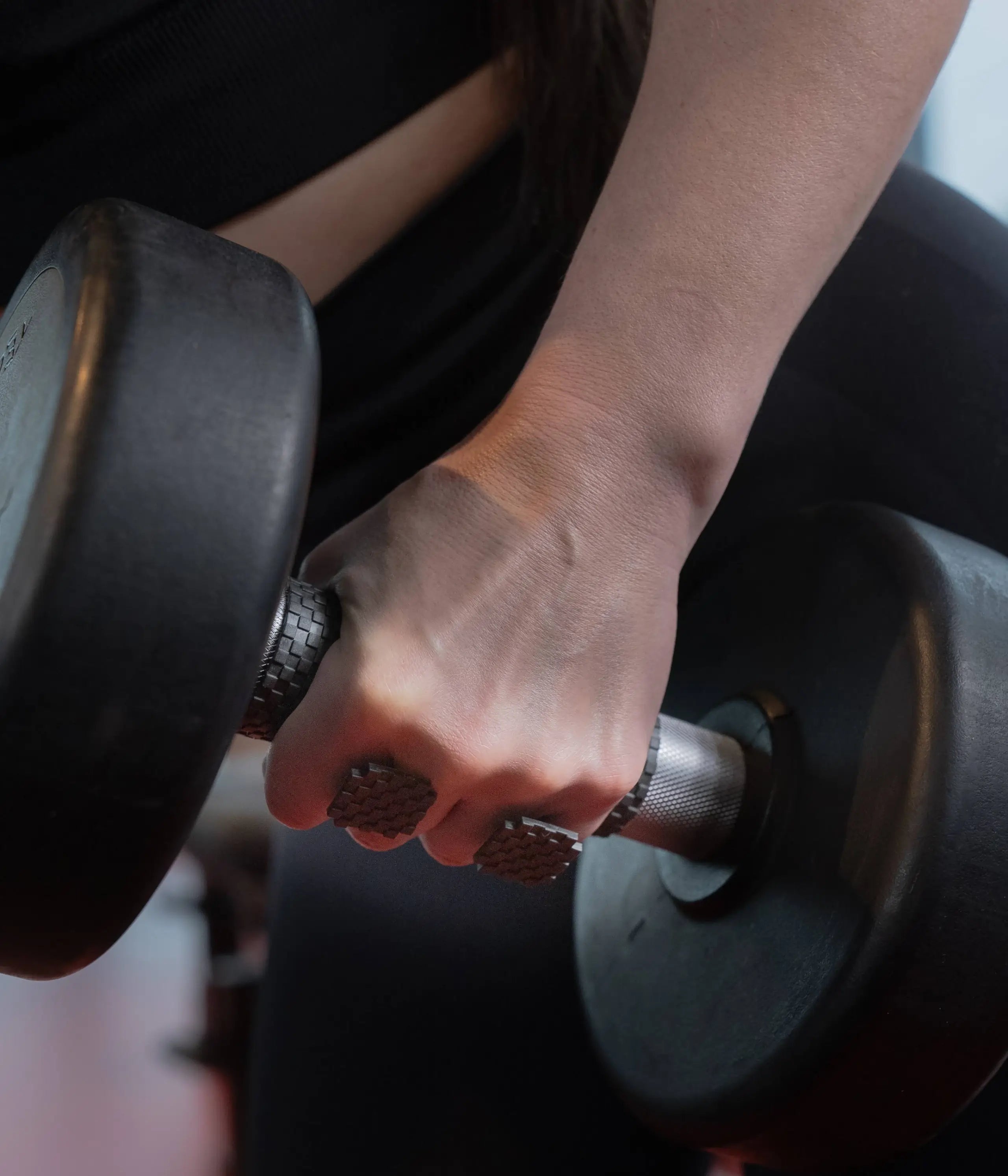 woman holding heavy dumbell while using sillygrip lifting grip pad